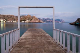 Пирс на Мраморном пляже. На вершине скалы в центре кадра видны остатки средневековой генуэзской крепости.