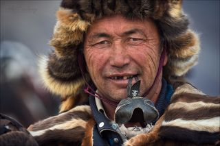 В зубах охотник держит кожаный клобучок ( называется «томагу» ), который одевают на голову беркута и тем самым закрывают ему глаза.
Основное его предназначение - он защищает птицу от ненужных внешних зрительных раздражений)