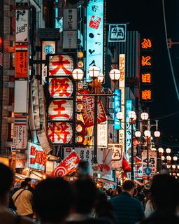 An atmospheric night shot in Dotonbori, where a traditional paper lantern and vibrant neon signs create a colorful composition.