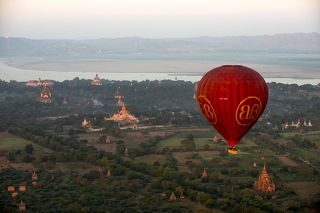 Воздушный шар над старым Баганом. Слева на снимке самые крупные и красивые баганские храмы:  Ананада (Ananda Pahto), 11-й век, за ним слева Табьиннью (Thatbyinnyu Temple, Храм вселенской мудрости, 15-й век. Это самый высокий храм Багана - 66 метров), Национальный археологический музей, справа от него пагода Бу Пхая (Bupaya Pagoda, построенная в 3-м веке и полностью восстановленная после землетрясения 1975-го года.) На заднем плане излучина реки Иравади.