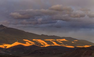 Но после обеда погода пошла на поправку и на небе появились облачка. К сожалению на горизонте клубилась сплошная облачность, а это означает только одно - полный швах. Но надежда была. Пока не поднялся дикий ветер и не загнал нас в палатку
Спустя какое-то время я заметил, как облака начали еле заметно окрашиваться. А для фотографа это сигнал - сейчас будет нечто крутое. И тут солнце нашло лазейку в плотной пелене, и вынырнуло где-то у самого горизонта. Что началось! Свет прожектором высветил холмы на горизонте.
Вот кусочек горной  гряды, снятой телеобъективом