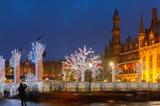 Decorated and illuminated Christmas tree on the rink in front of Province Court at Market Place in the center of Bruges at night, Belgium