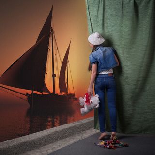 Фото посвящено 14-летию дочери. Этот возраст-некий рубеж между детством и взрослой самостоятельной жизнью. Занавес олицитворяет этот рубеж, безбрежный океан-взрослую жизнь, ждущую её впереди, где она будет самостоятельно курсировать как \'этот парусник. Она уже частично готова, а частично ещё в своём детстве.