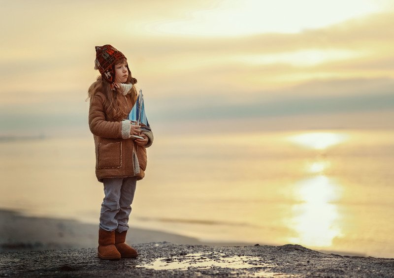 море вечер зима побережье девочка детство теплая одежда грусть кораблик игрушка штиль мечтательницаphoto preview