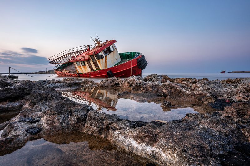 Greece; Kithera; Kithira; blue; boat; coast; dusk; old; red; reflection; rock; rusty; sea; shipwreck; sky; stone; stranded; water Red Boat Stranded on Kythera islandphoto preview