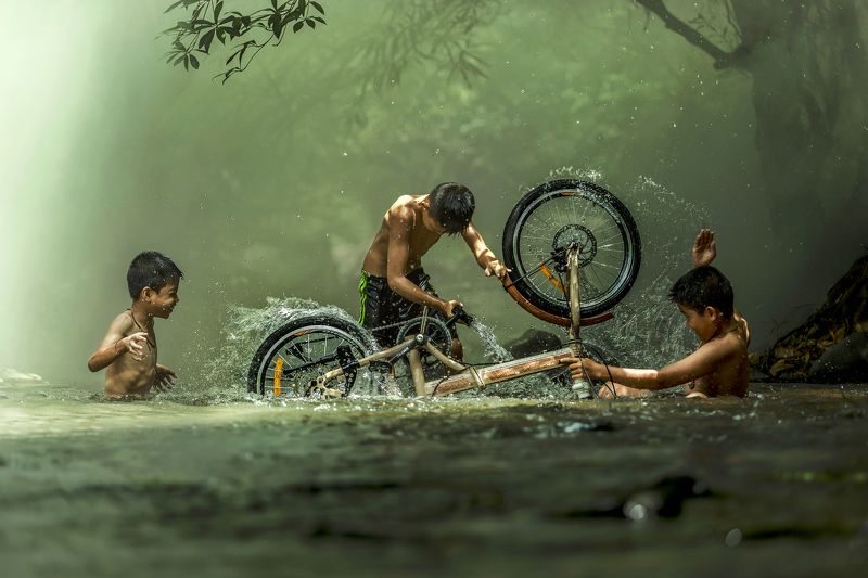 #summer. #Bicycle #Candid #Child #Children Only #Color Image #Day #Horizontal #Outdoors #People #Photography #Pre-Adolescent Child #Real People #Sunlight #Thai culture #Three Boys #Togetherness #Tradition #Transportation #Two People #Wading #Washing #Wate The boys are washing bicycle playfully River Near Homephoto preview