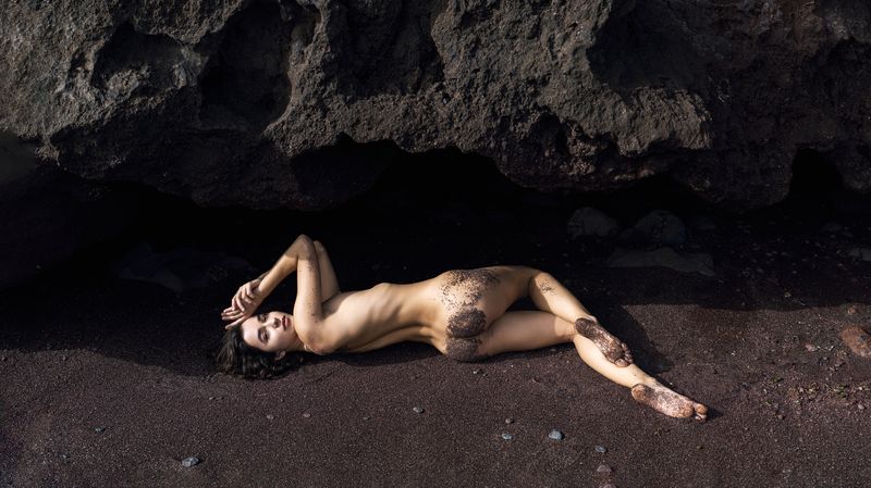 artistic nude, back view, beach, beauty in nature, body pose, captivating gaze, cliff, femininity, grace, looking at camera, lying down, naked, one person, outdoors, red stone, relaxation, rocks, sand, seductive appeal, sensuality, stones, young woman Sand and Serenityphoto preview