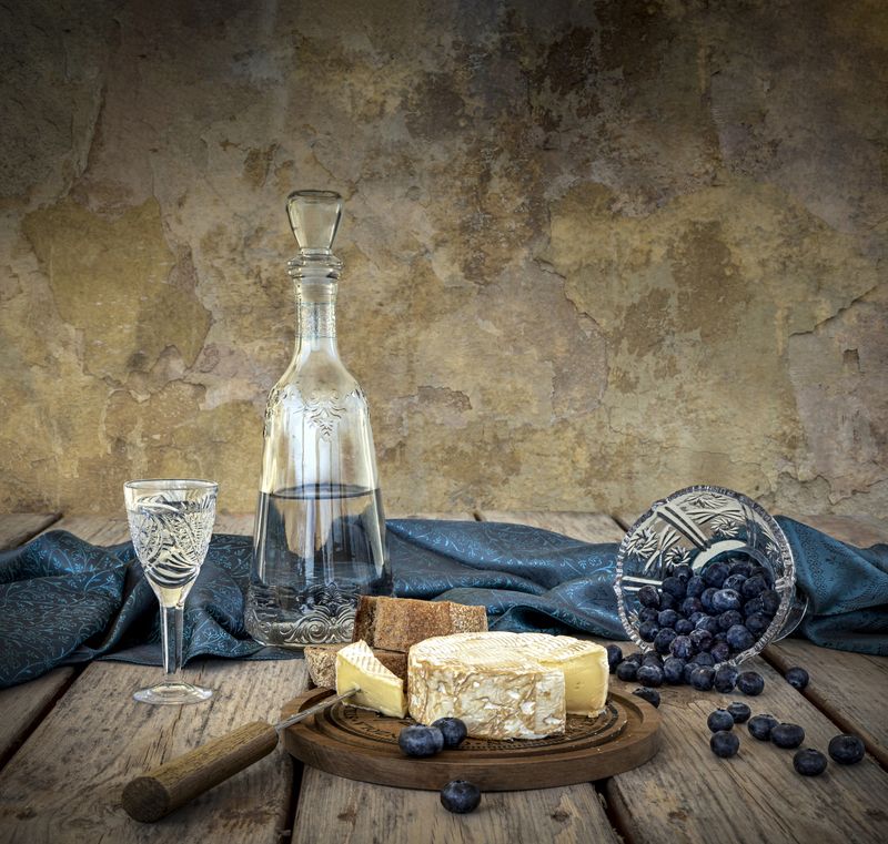 Водка, голубика, креманка, драпировка, стена, деревянный стол, нож, сыр, дощечка. Рюмка водки на столе...photo preview