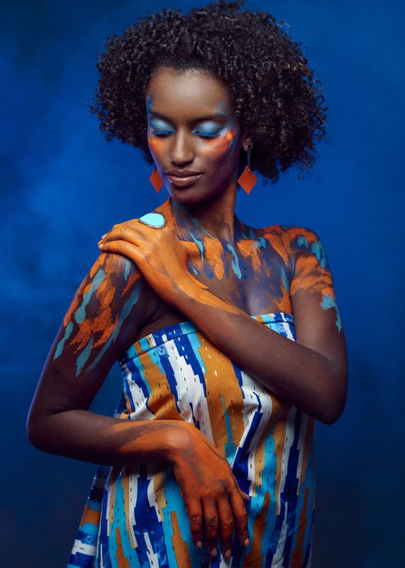african beauty, amber accents, artistic portrait, body art, creative makeup, curly hair, dark skin, delicate pose, earrings, ethnic style, exotic elegance, female portrait, front view, painted body, shoulder touch, smoke, vibrant colors, young woman Colors of Addisphoto preview