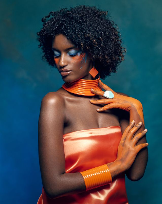 african beauty, amber accents, blue eyeshadow, body art, bracelet, creative makeup, curly hair, dark skin, delicate grace, earrings, elegant pose, ethnic style, exotic elegance, female portrait, front view, necklace, painted body, vibrant colors Portrait of a Modern Shebaphoto preview