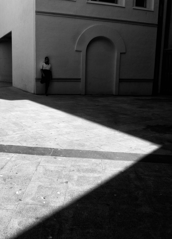 monochrome, black_and_white, bnw, high_contrast, street_photography, fine_art, minimalism, abstract, candid, light_and_shadow, shadows, sunlight, geometric_shapes, diagonal, line, architecture, courtyard, wall, archway, solitude, lonely, person, figure, u luz, sombra y figuraphoto preview