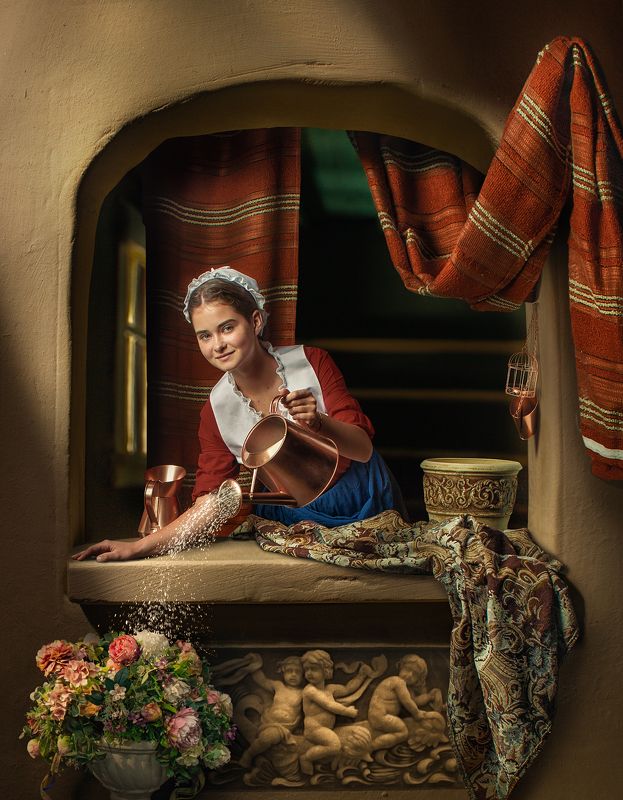 A young girl at a window ledge watering flowersphoto preview