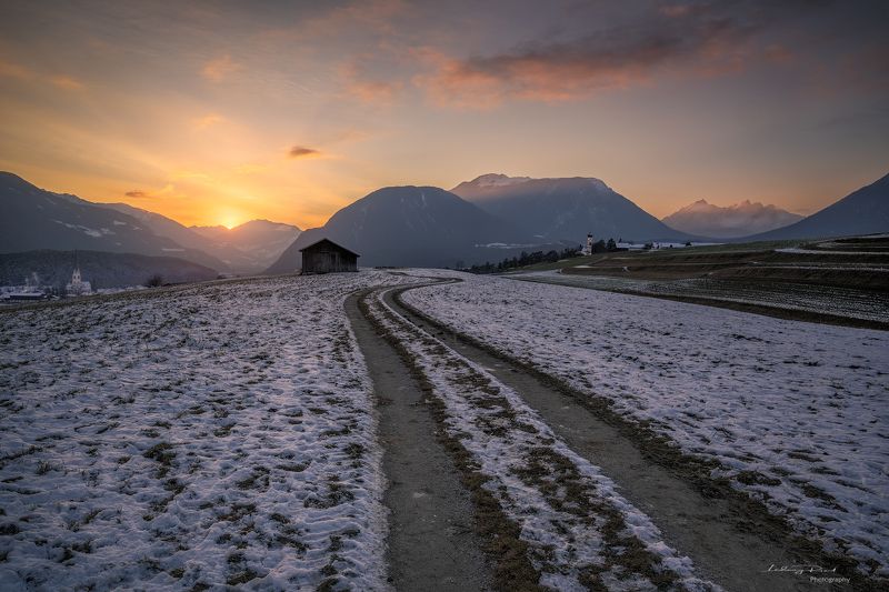acres, agicutural building, agriculture, alps, austria, austrian alps, bend, bending road, church, clouds, evening, evening glow, farmhouse, fog, foggy, forest, gravel road, hey barn, hill, hills, houses, landscape, meadows, meandered, meandered road, mie Just Beyond the Sunsetphoto preview